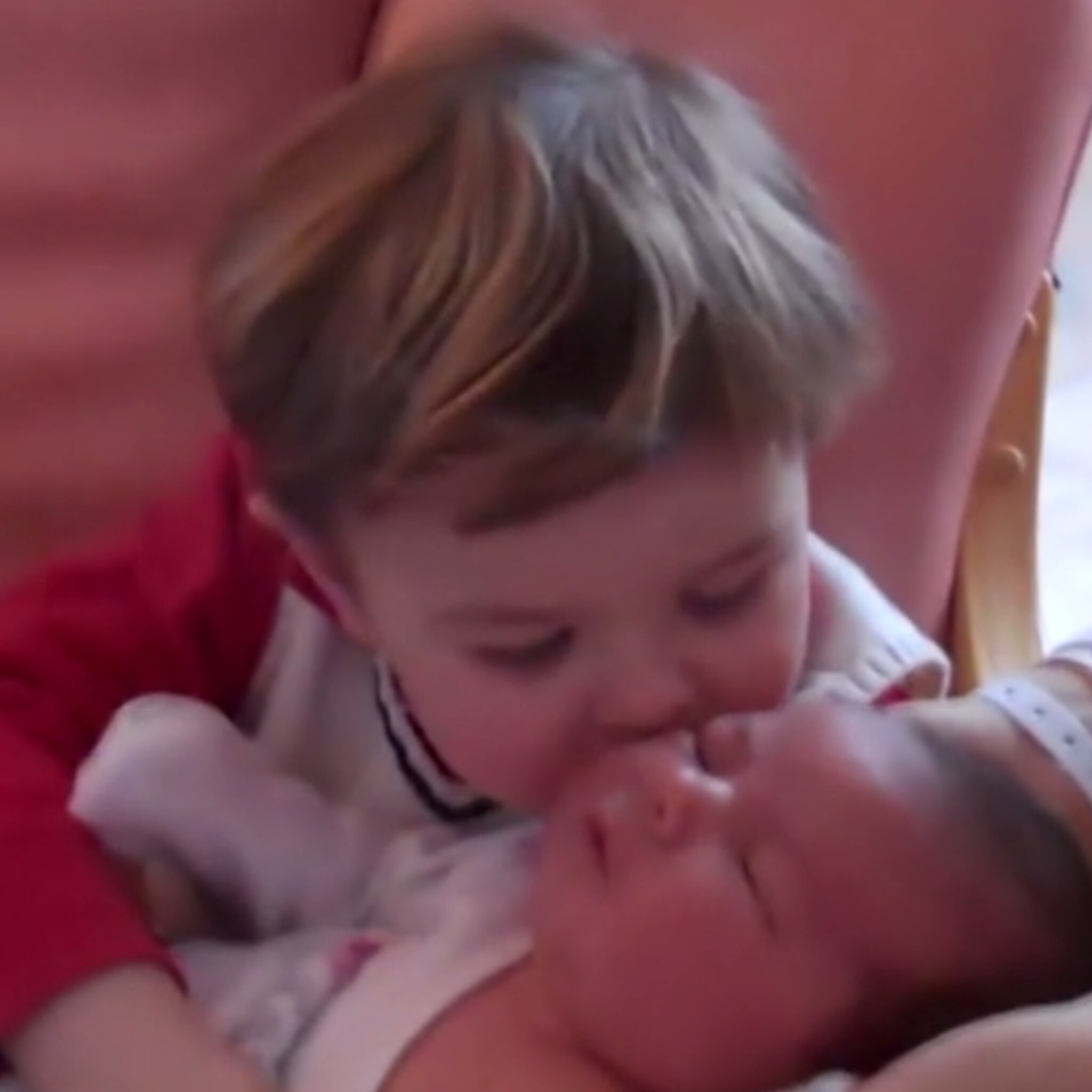 lief jongetje probeert gesprek te voeren met pasgeboren zusje