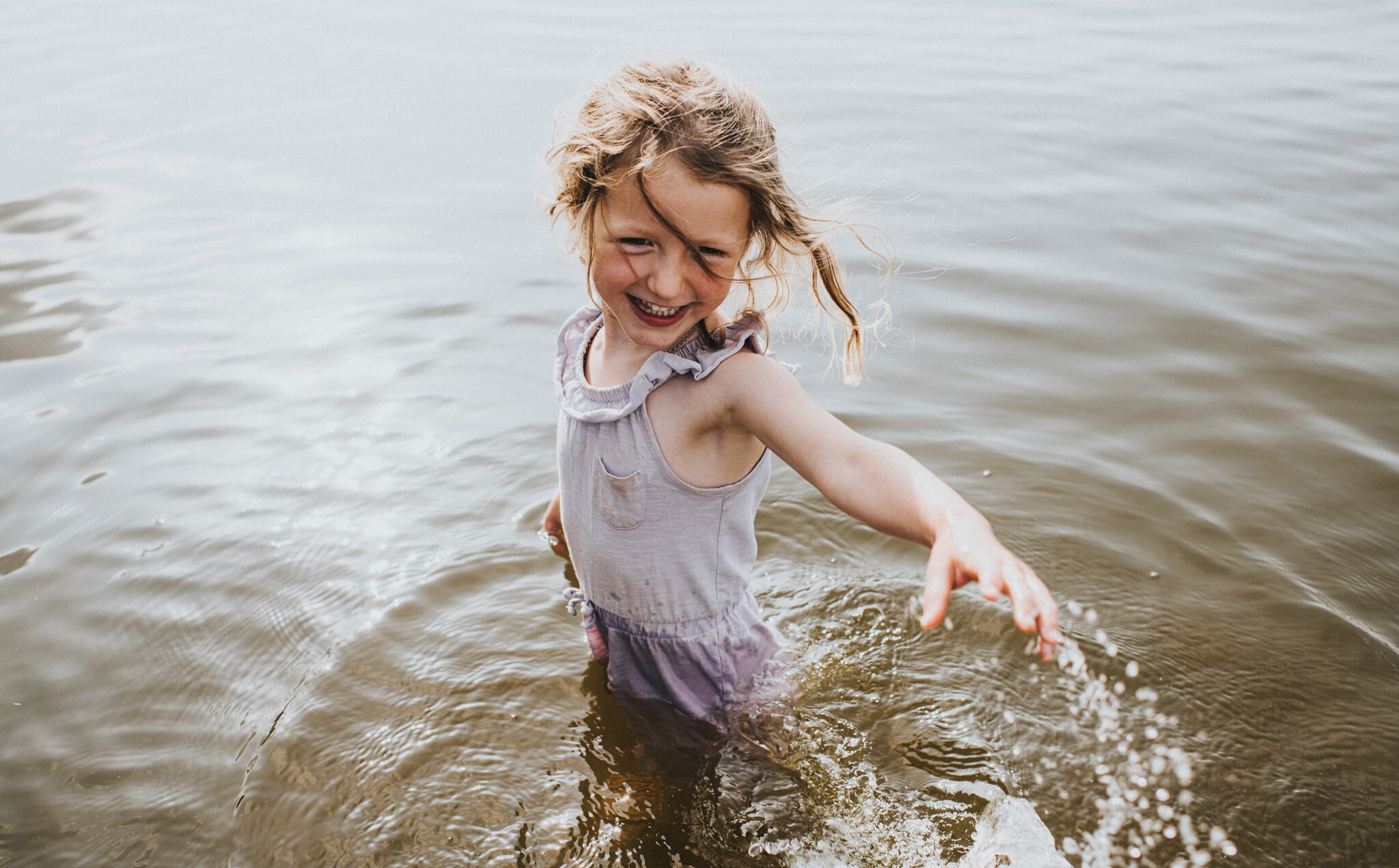 Cute young girl intentionally splashes someone in a lake while laughing. Getty Images