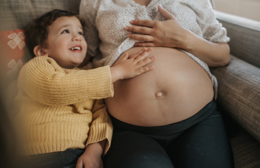 Boy touching his pregnant mother's belly Getty Images