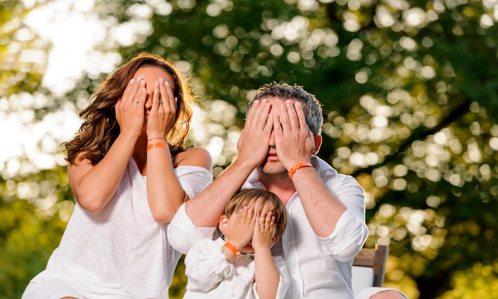 playful family hidind and covering faces. Getty Images
