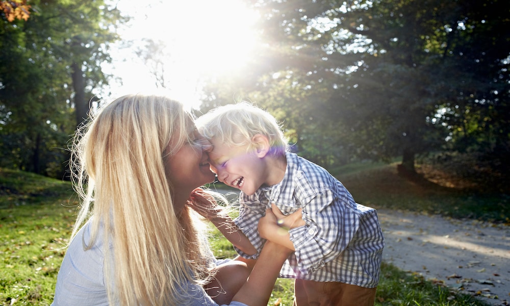 portrait of a young blond woman and her little boy cuddling and having fun on the meadow of a park on a sunny day. Getty Images