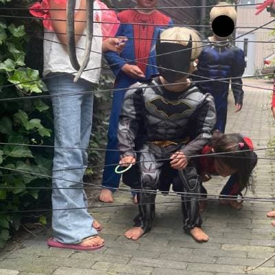 Kind in Batmanpak probeer door gespannen touwen te klimmen Ouders van Nu