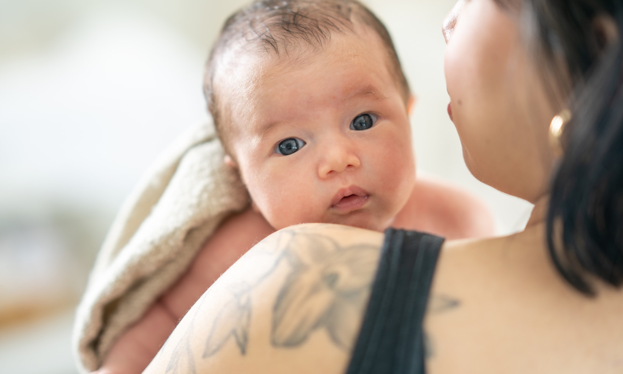 Moeder met baby die over haar schouder kijkt. Getty Images