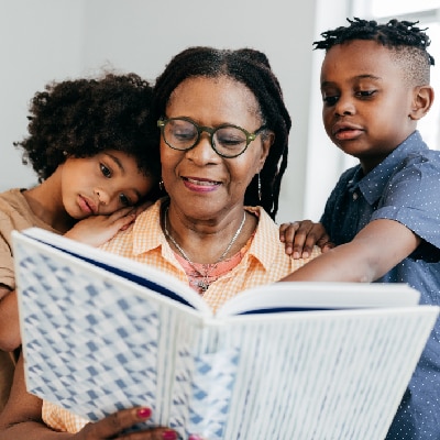 Vrouw leest boek met twee kinderen naast zich Getty Images