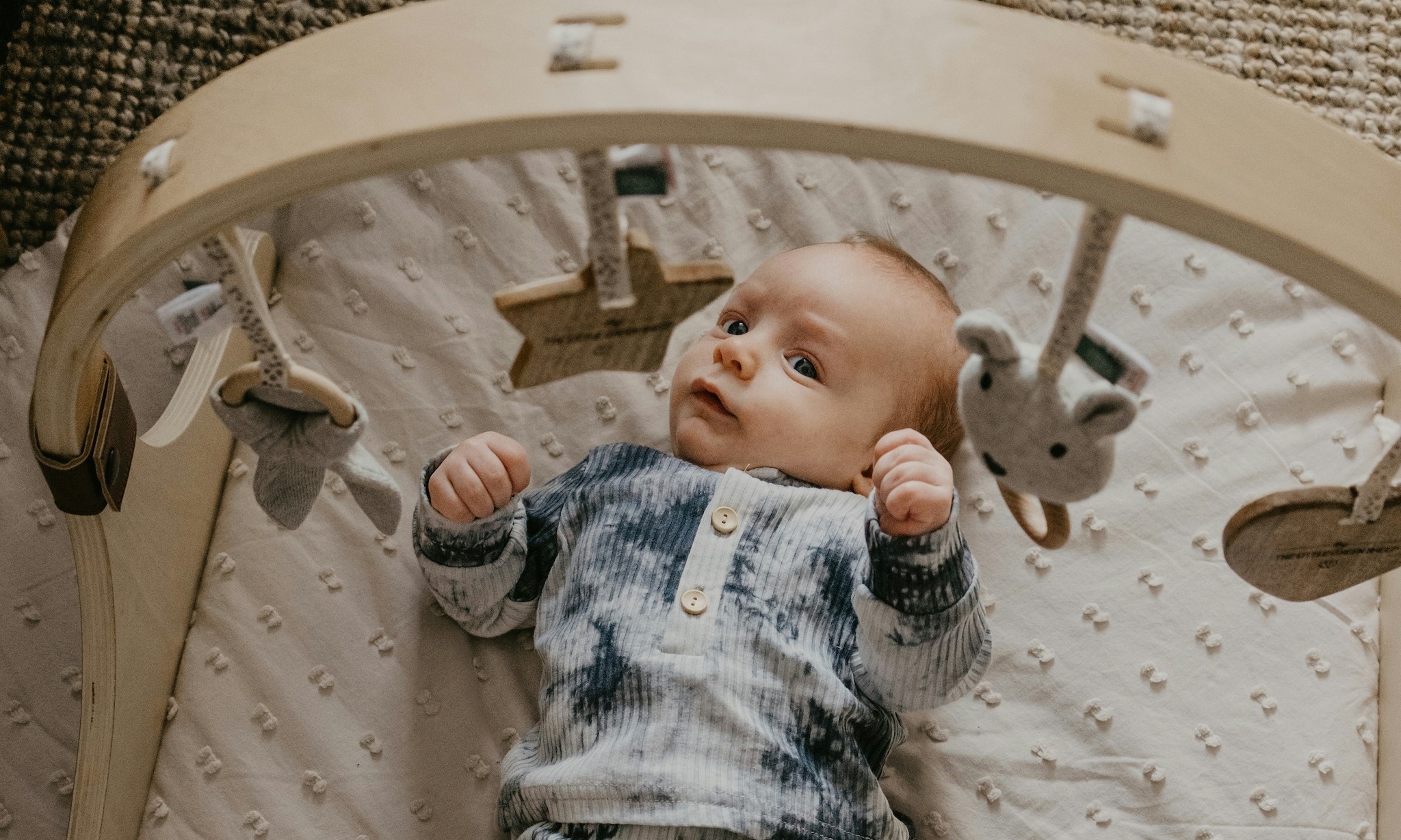baby ligt onder houten babygym om ermee te spelen Getty Images