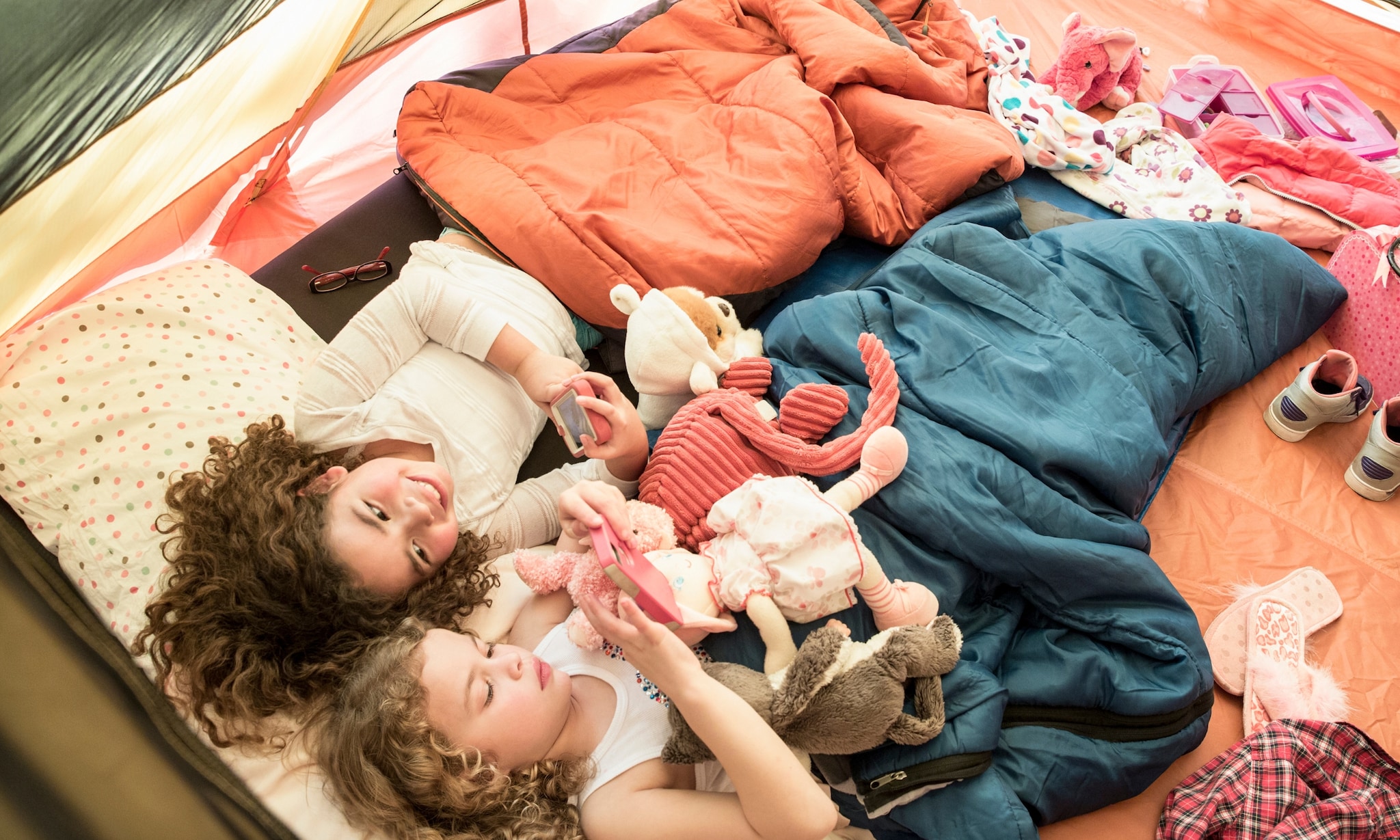 twee meisjes kamperen en liggen in kinderslaapzak Getty Images
