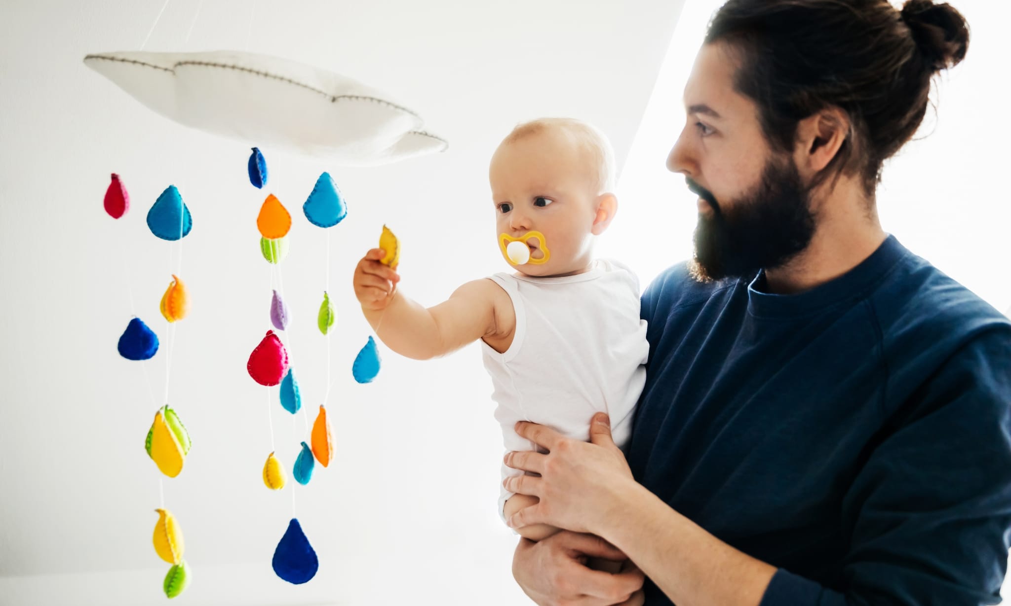 vader bekijkt muziekmobiel met baby Getty Images