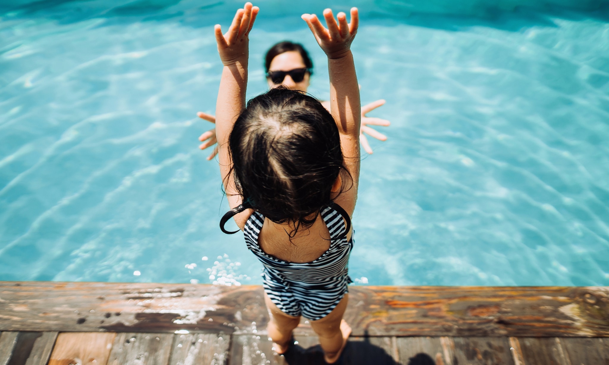Kind en ouder bij rand zwembad - schuldgevoel tijdens de zomervakantie Getty Images