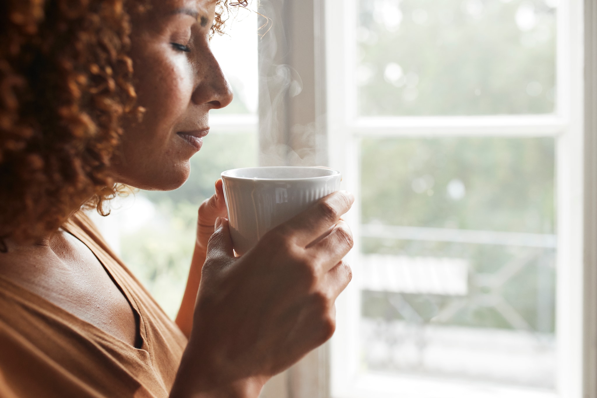 Mature woman smelling coffee at home Getty Images