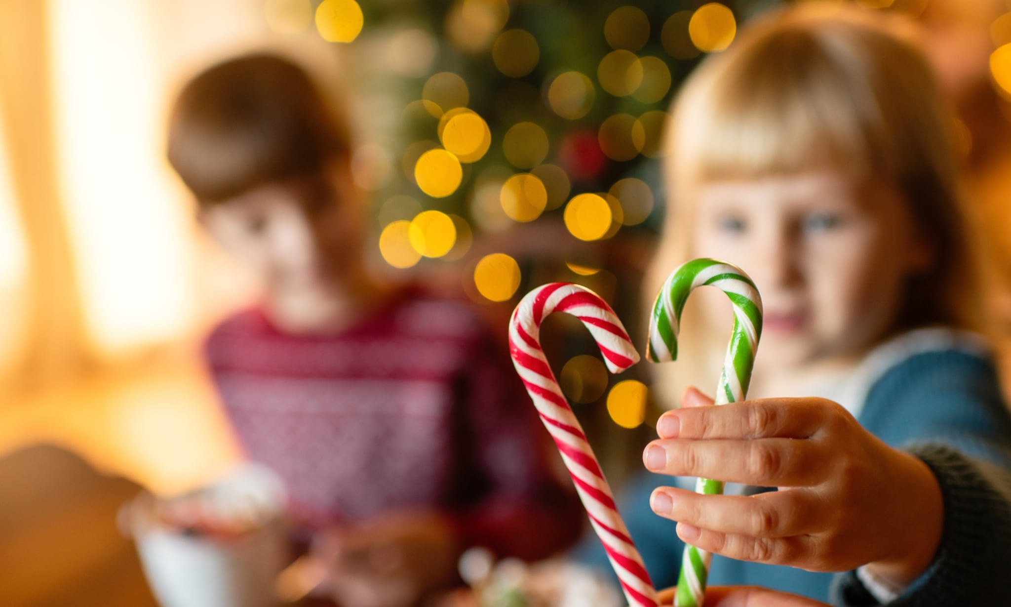 kind maakt een hartje van zuurstokjes voor de kerstboom, symbool voor goede doelen cadeaus Getty Images