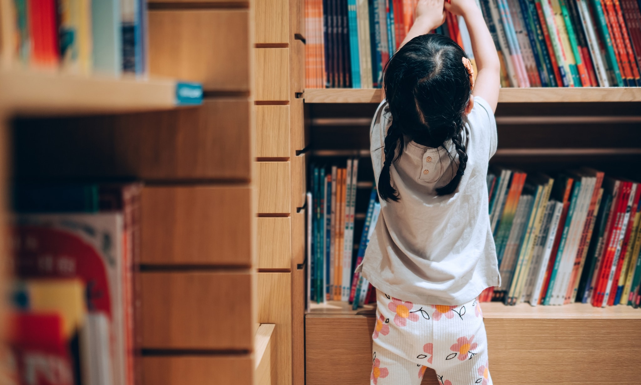 meisje in bibliotheek zoekt inclusieve kinderboeken met diversiteit Getty Images
