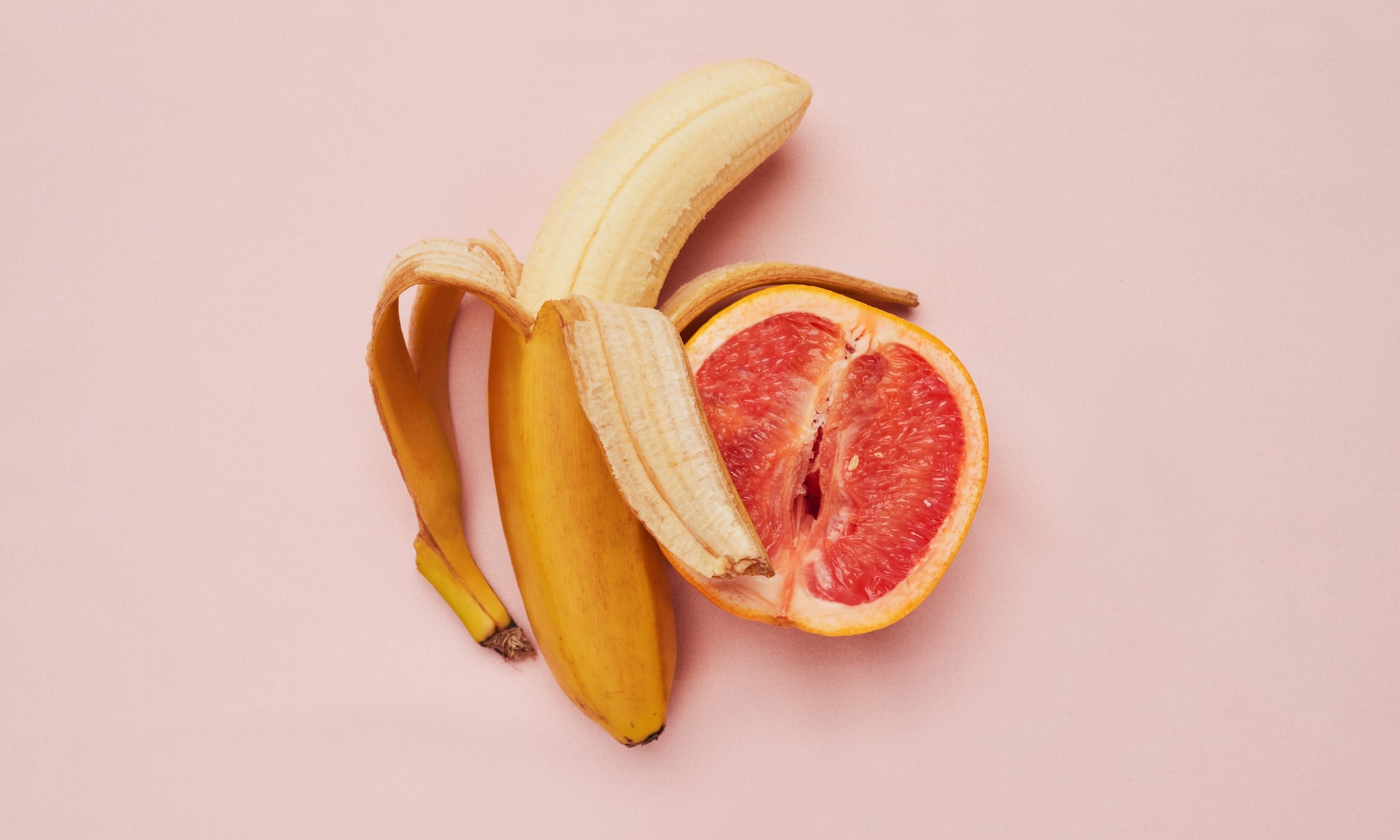 Banaan en grapefruit bij rubriek Seksdagboek, roze achtergrond. Getty Images