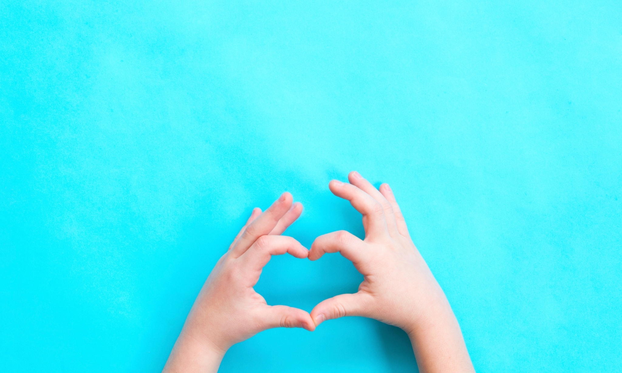 Kinderhanden vormen een hart, met blauwe achtergrond. Getty Images