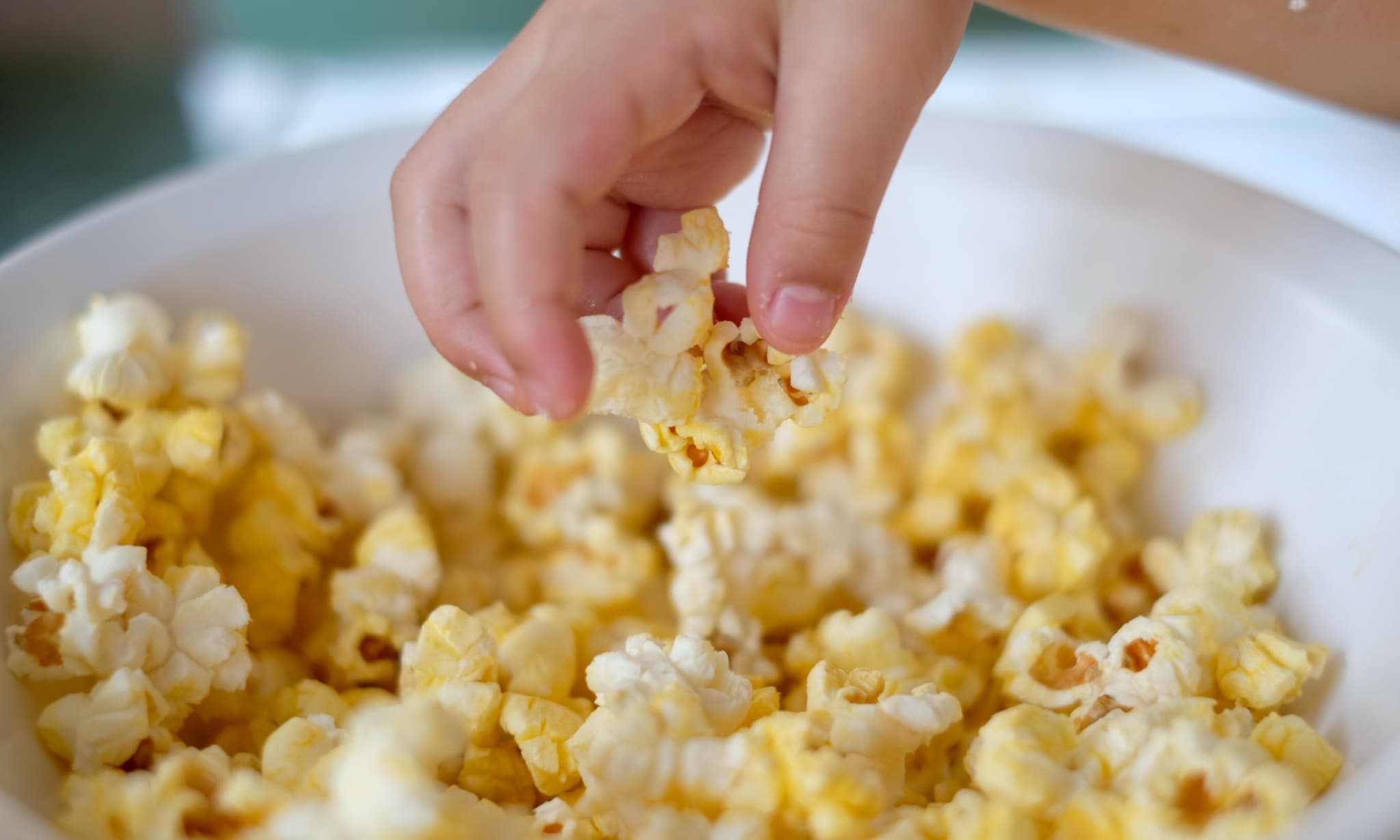 Kinderhand graait in popcorn. Getty Images