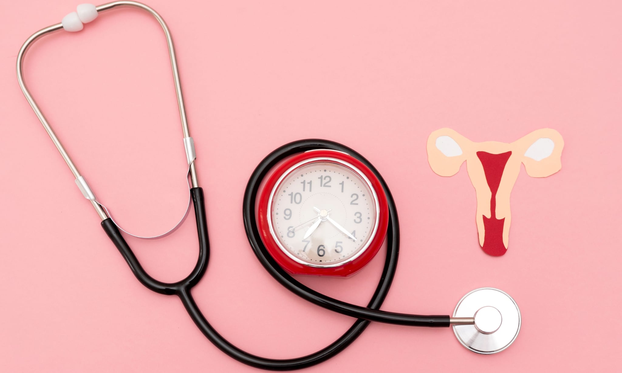 Stethoscoop, klok en papieren baarmoeder als illustratie bij artikel over perimenopauze na bevalling. Getty Images
