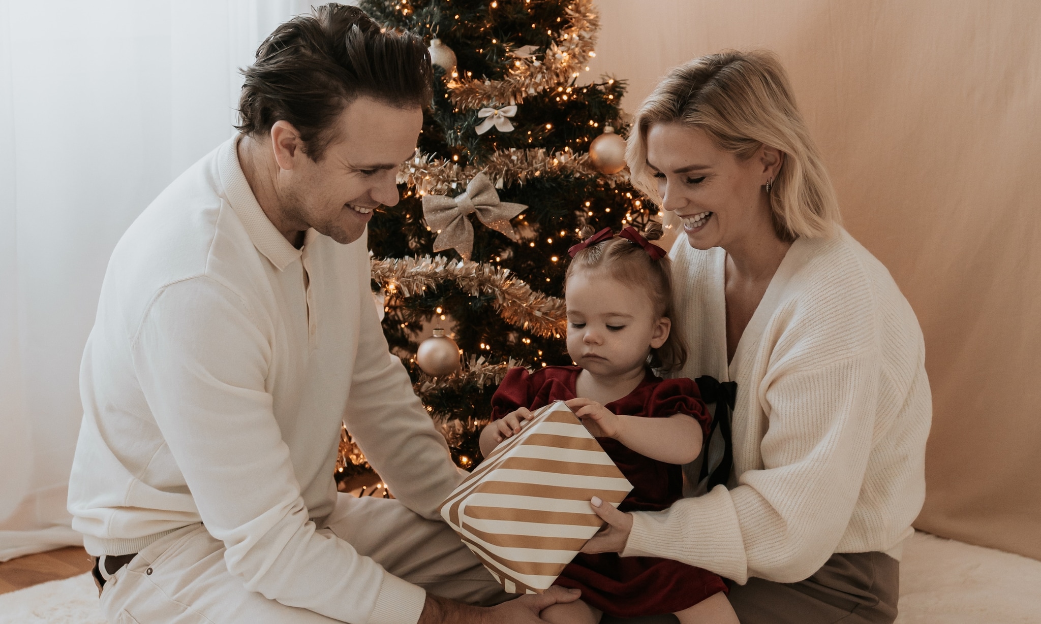 Influencer Carmen van Weersel met haar gezin voor de kerstboom, ze vertelt over haar favoriete baby- en peuterproducten foto: Momenten door Kim