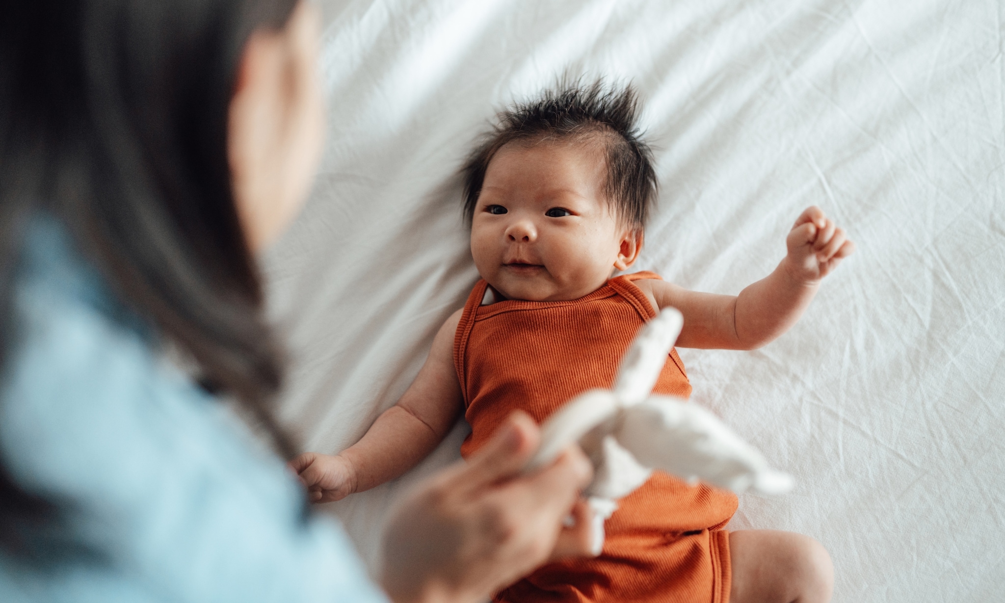 Moeder speelt met baby en gebruikt een van de producten die niet op elke babyuitzetlijst staan (maar wel superhandig zijn) Getty Images