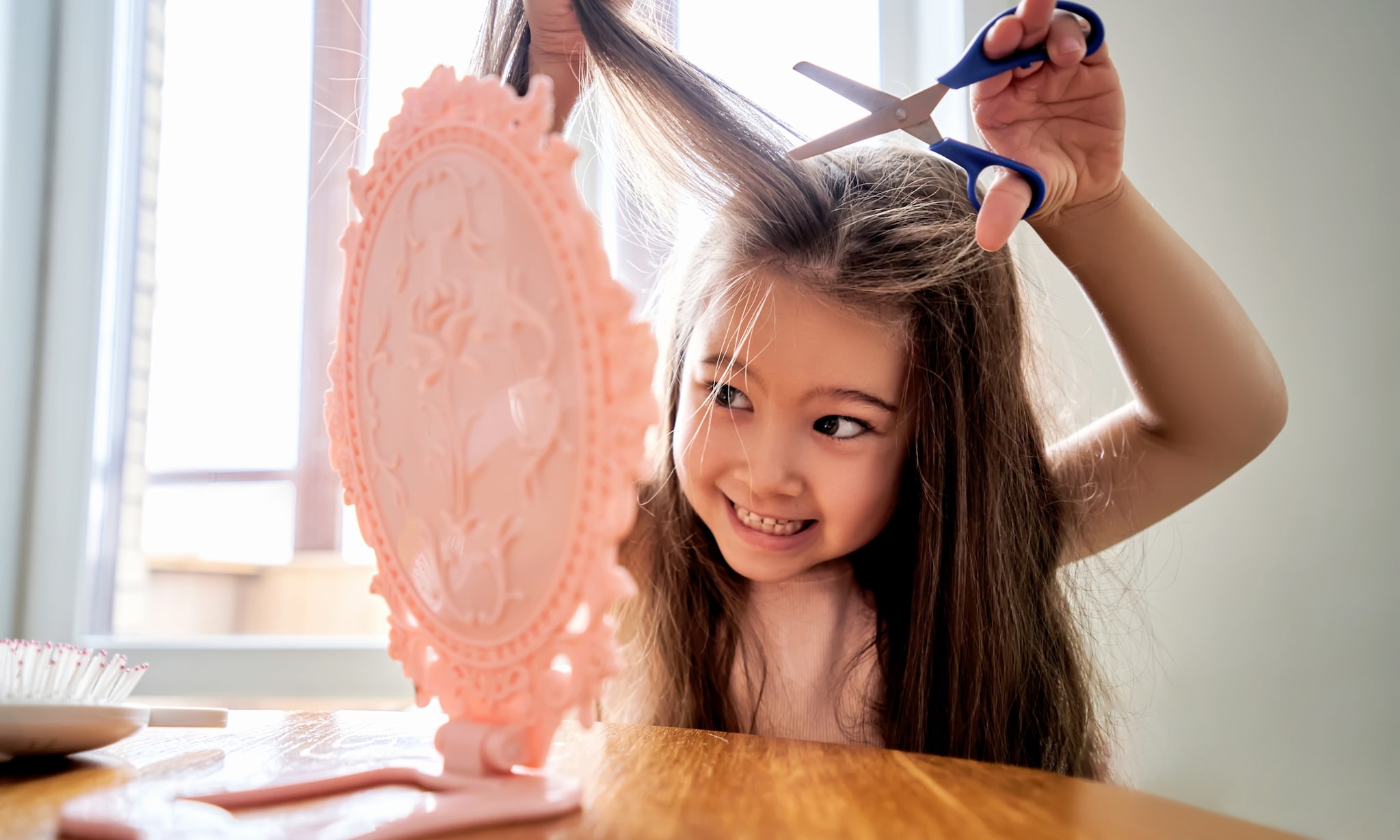 Meisje knipt haar eigen haar voor spiegel. Getty Images