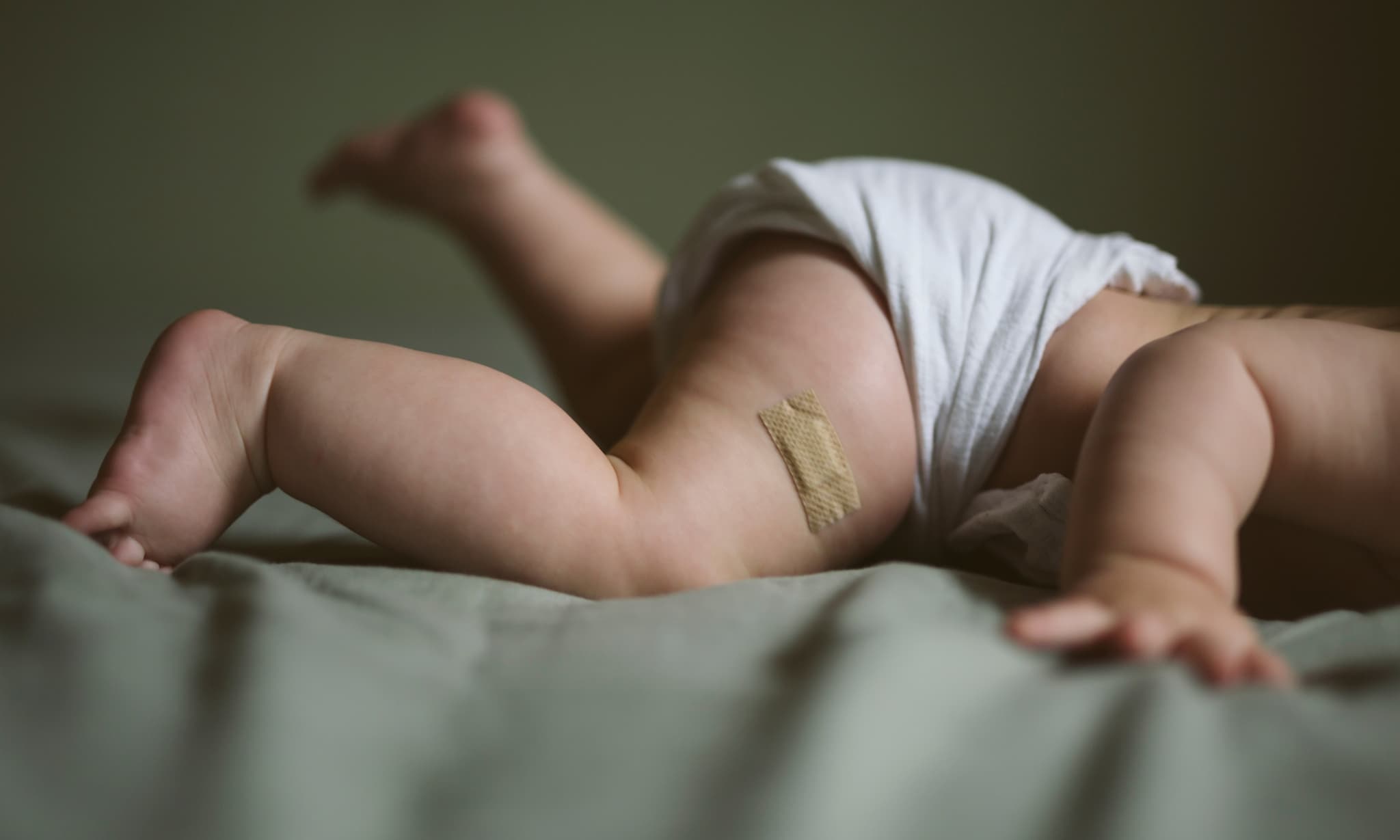 Baby op de buik met alleen de benen zichtbaar, bij nieuws over geen vitamine K-prik voor baby's. Getty Images