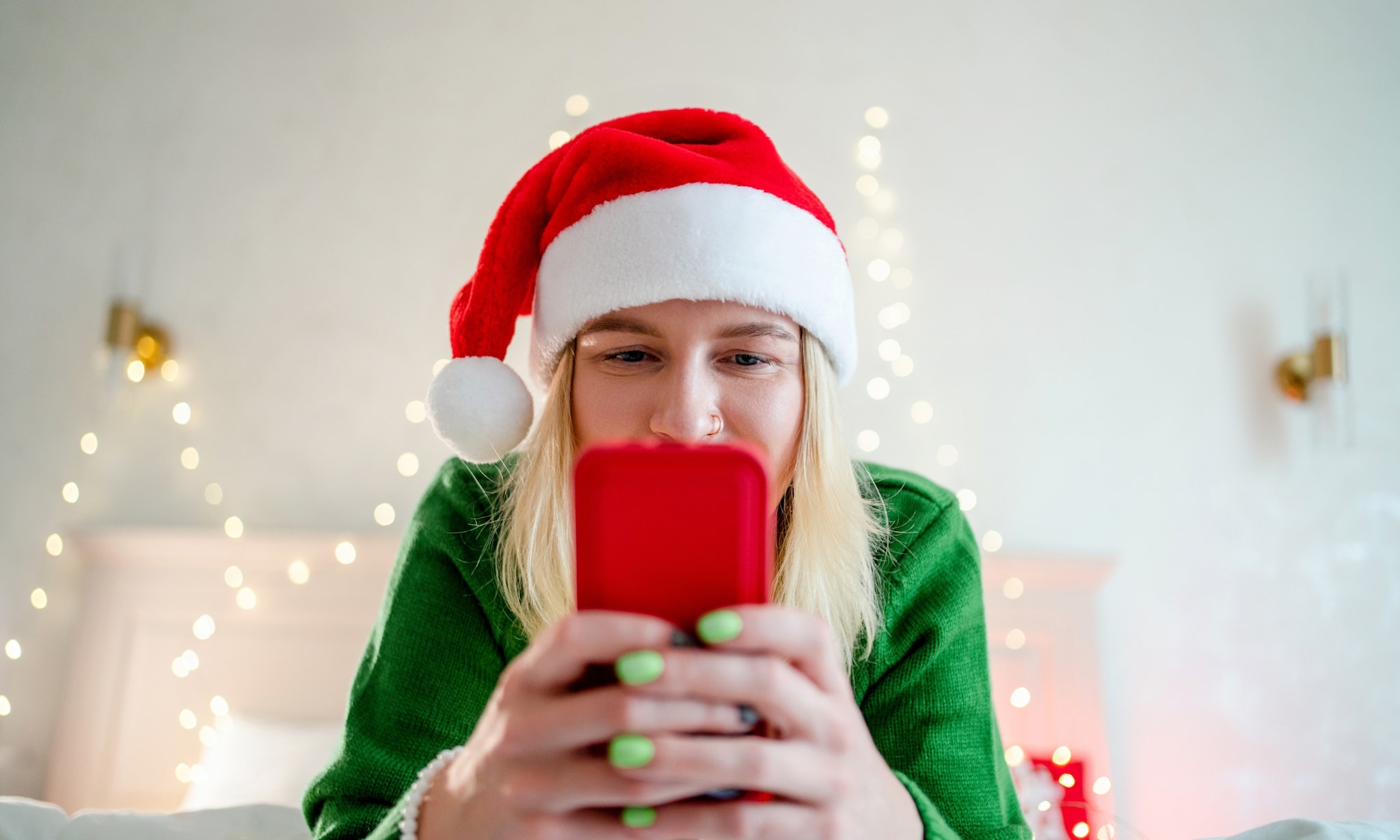 Vrouw met kerstmuts leest op haar telefoon. Getty Images
