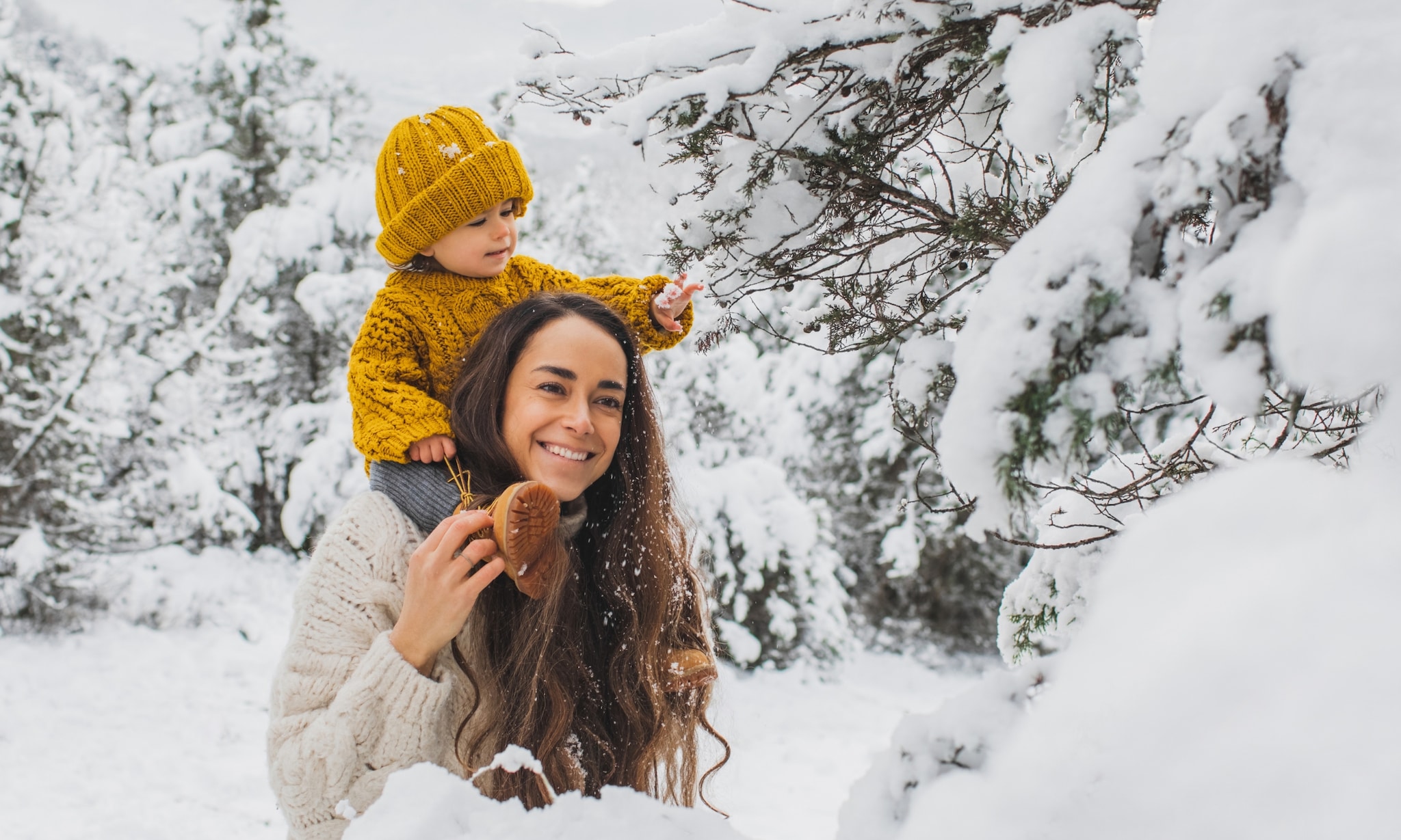 Moeder met klein kind op de schouders in de sneeuw. Getty Images