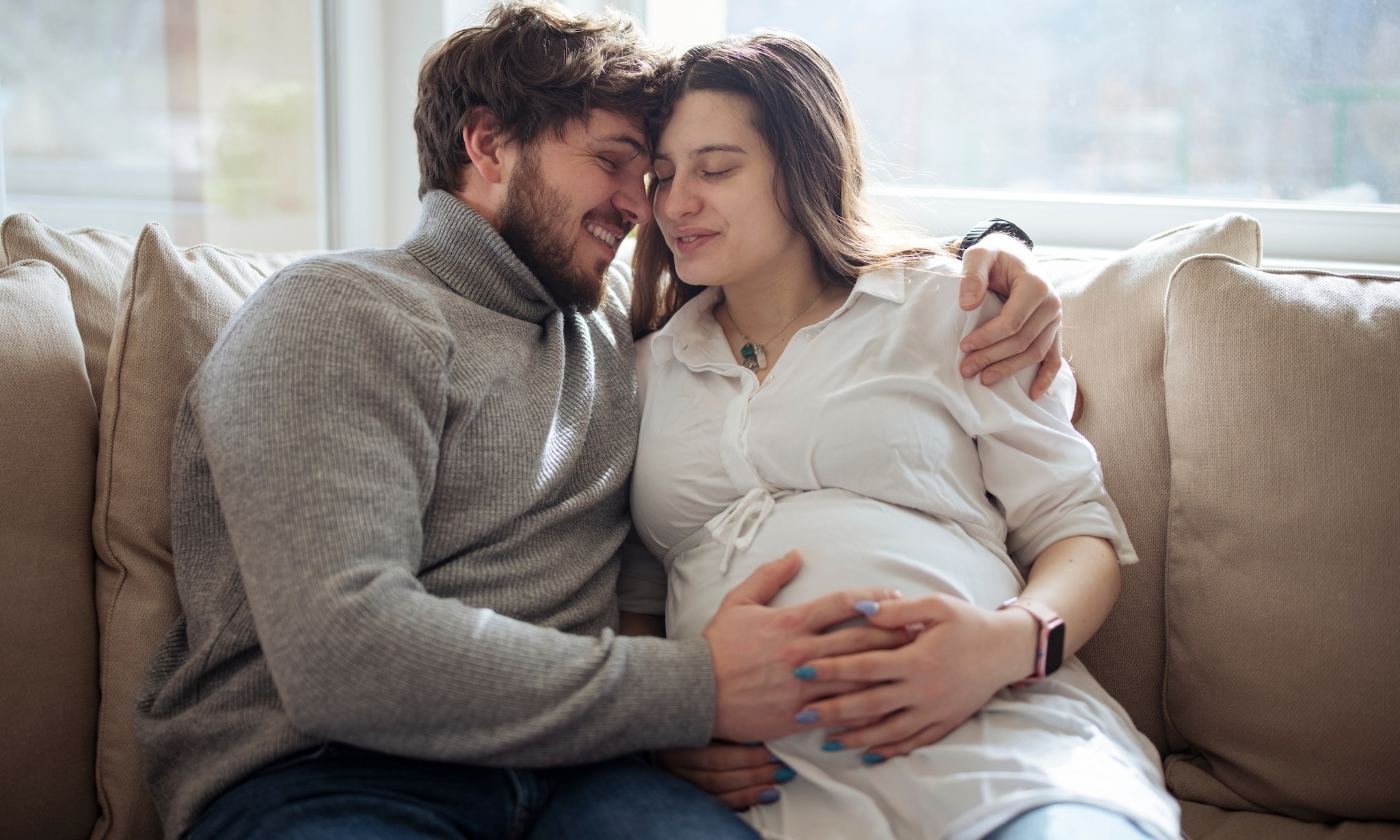 Zwangere vrouw en partner samen op bank Getty Images