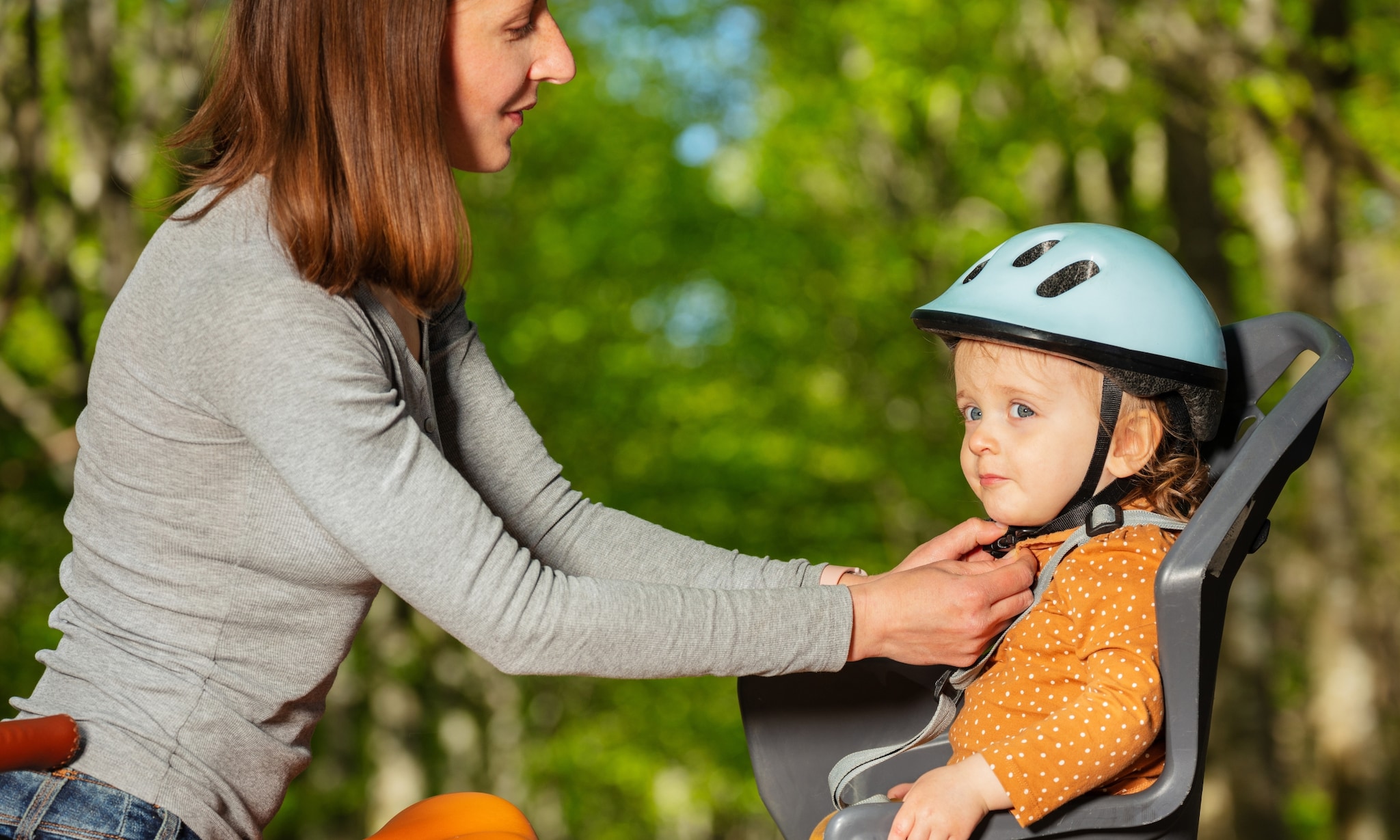 moeder zet kind in fietsstoeltje, hier moet je op letten als je een fietsstoeltje koopt Getty Images