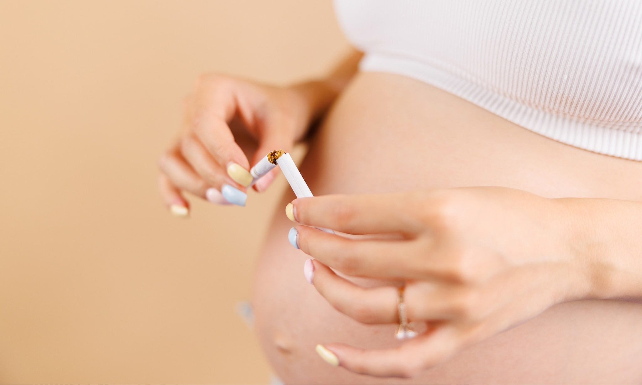Zwangere vrouw breekt sigaret door om te stoppen met roken. Getty Images