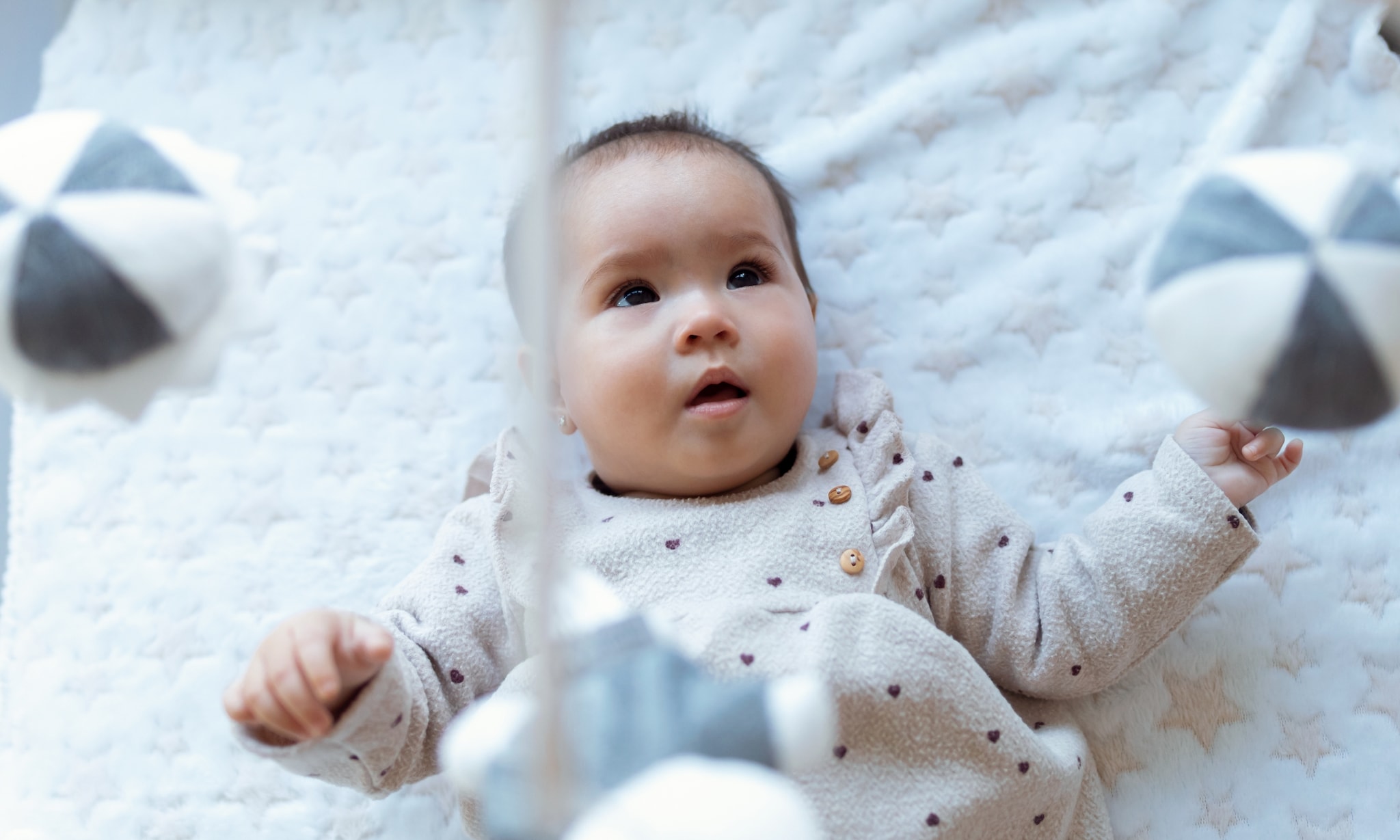 baby ligt in box en kijkt naar muziekmobiel, hier let je op voor aanschaf Getty Images