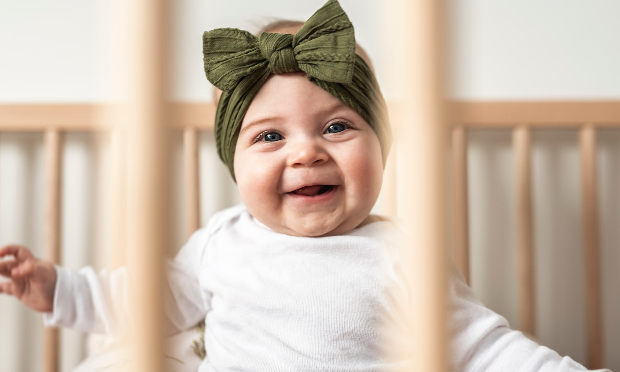 baby zit lachend in veilige babybox, hier moet je op letten als je een box koopt Getty Images