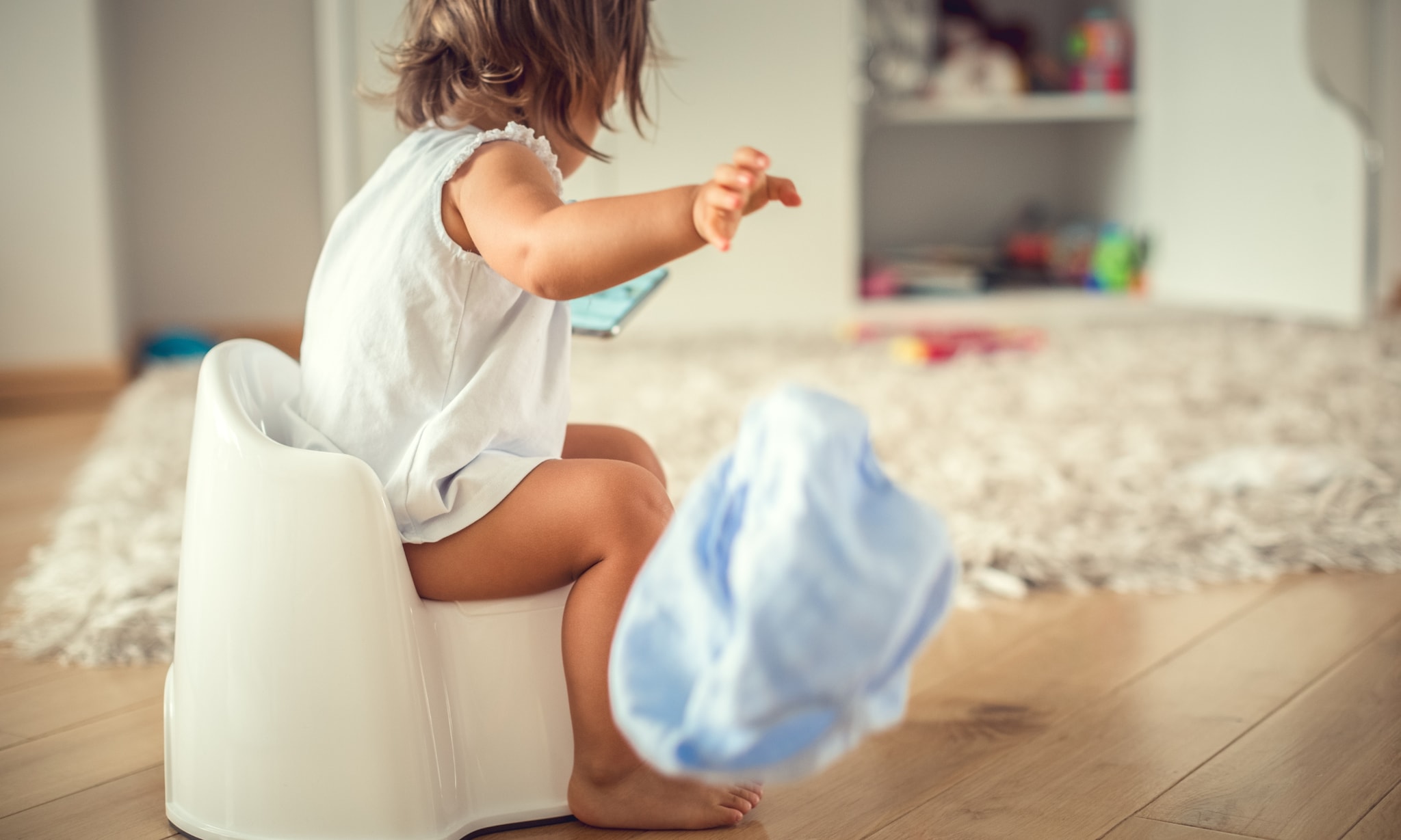 meisje zit op plaspotje en gooit met luier, hier moet je op letten als je een plaspotje koopt