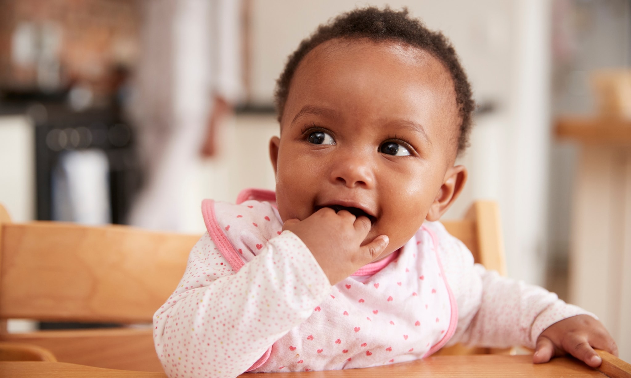 Baby draagt slab en zit in kinderstoel van Stokke Tripp Trapp.